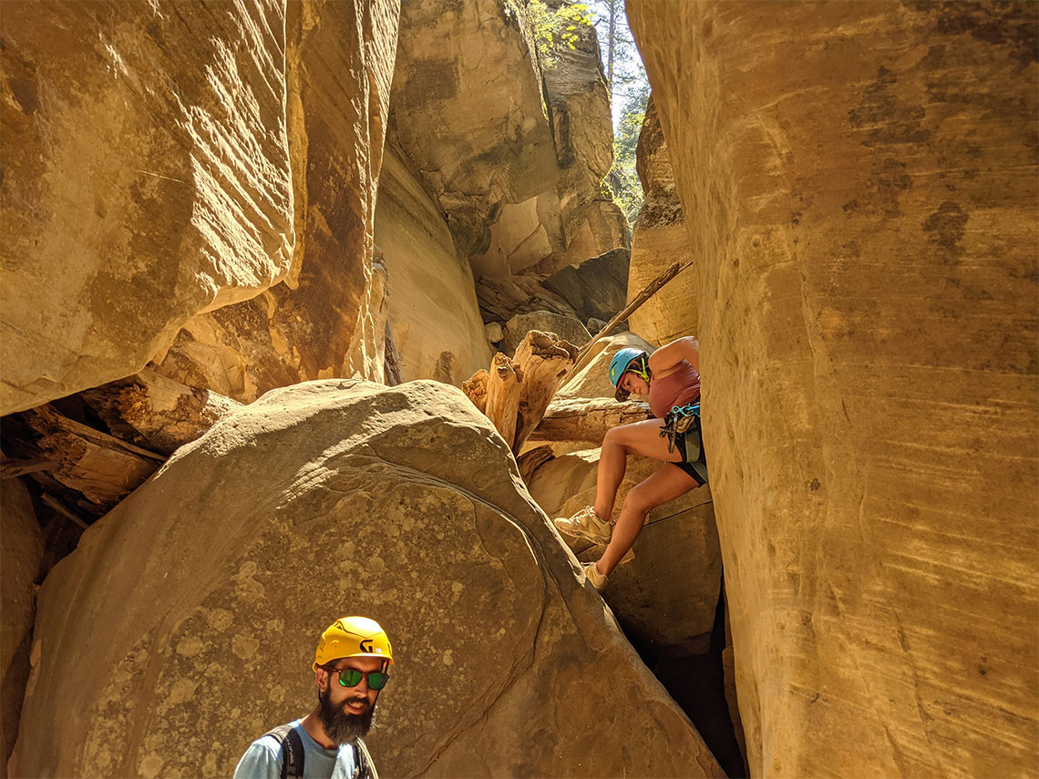 A person begins downclimbing in Englestead Hollow Canyon