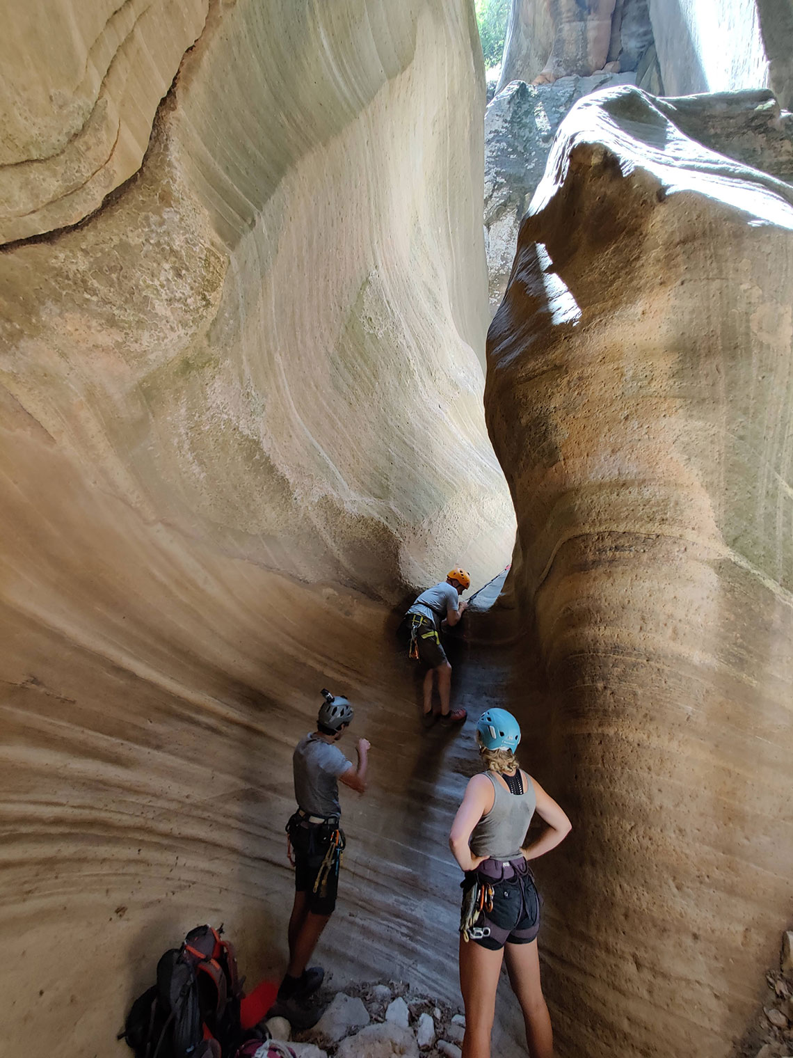 Person downclimbing into a pothole in Englestead Canyon